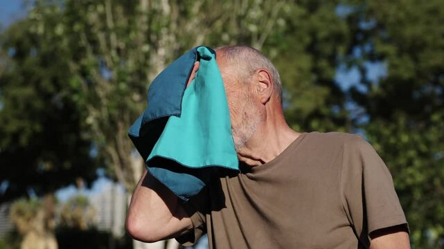 Senior man wiping sweat from forehead in slow motion