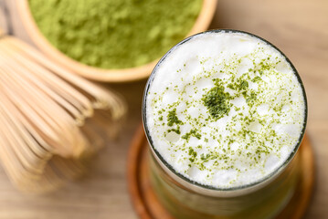 Matcha green tea with foam milk in glass on wooden background