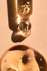 Obraz premium Pipette with a drop of liquid product, hyaluronic acid, essential oil on a beige background, top view, macro.