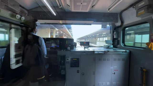 Train operator inside the cockpit of a high-speed train approaching a station in Tokyo