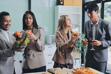 Asian office colleagues and friends enjoy a daytime BBQ with pizza and beer, celebrating Halloween and cheering for their favorite soccer team, creating a lively atmosphere filled with joy.