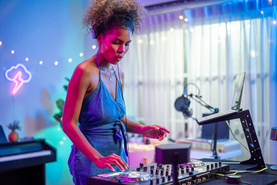 African American woman DJ mixing and scratching music mixer controller. 
