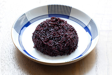 Steamed riceberry rice in white dish on wooden background
