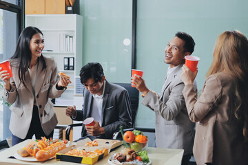 Asian office colleagues and friends enjoy a daytime BBQ with pizza and beer, celebrating Halloween and cheering for their favorite soccer team, creating a lively atmosphere filled with joy.