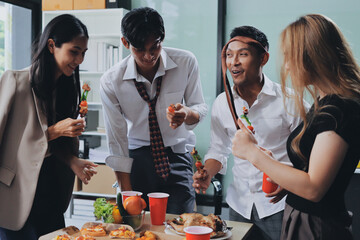 Asian office colleagues and friends enjoy a daytime BBQ with pizza and beer, celebrating Halloween and cheering for their favorite soccer team, creating a lively atmosphere filled with joy.