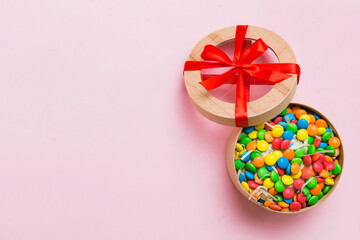 Set of different sweet candy in a paper box with a satin ribbon on a colored background. Holiday concept