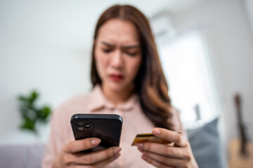 Asian frustrated woman making online payment failure on phone at home.