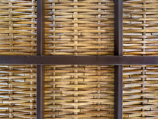 Close up photo of beautiful hand woven synthetic rattan texture in natural brown colors. Wicker rattan with dark wood frame panel. Seamless background texture.