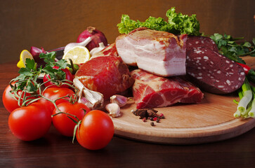 Meat products, bacon and sausages surrounded by vegetables and greens on a cutting board.