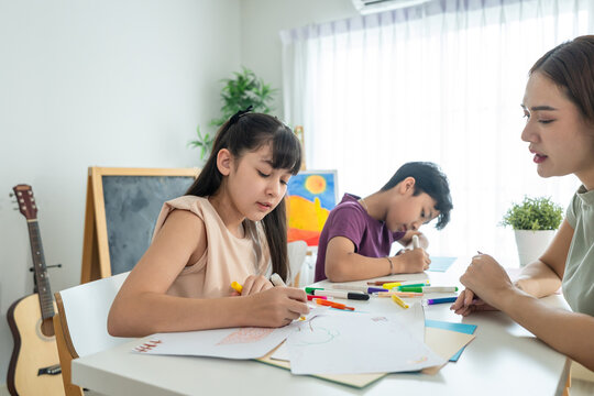 Asian teacher educating students in an art class at elementary school.