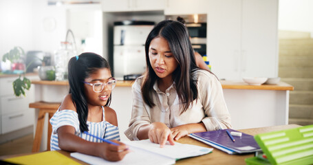 Mother, girl and homework with book on table for learning assessment, knowledge and support in education. Happy, family and woman with child in house for development, homeschool or help with studying