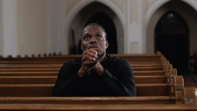 Young man praying with rosary in church