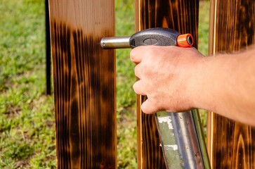 Treating wooden planks with fire from a gas cylinder.