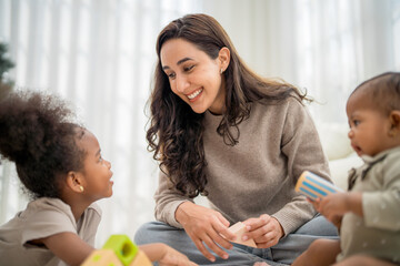 Smiling caregiver interacts with two children during playtime in a bright indoor setting