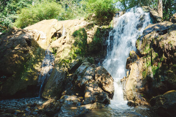 A serene waterfall cascades over rocks, surrounded by lush greenery, in Tak Thailand.