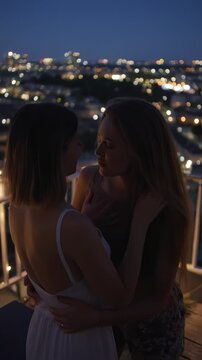 Romantic Rooftop Kiss: Two Young Women in Love Embrace the City Nightlife in a Vertical Video