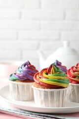 Delicious cupcakes with colorful cream and tea on pink table, closeup. Space for text