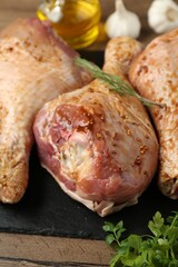 Raw marinated turkey drumsticks on wooden table, closeup