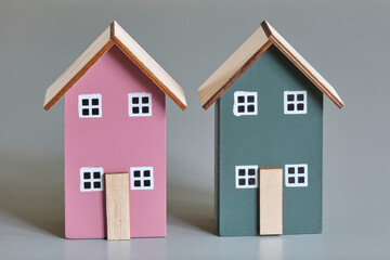Two miniature houses in red and green on a gray background. Real estate industry, affordable housing, mortgage, eco-friendly, energy neutral and building insulation concept.	