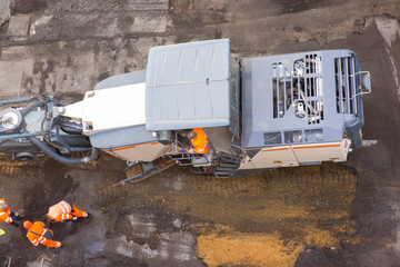 Top view of workers resurfacing road asphalt. Large industrial machine at work.
