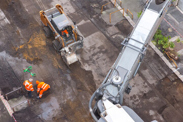 Top view of workers resurfacing road asphalt. Large industrial machine at work.