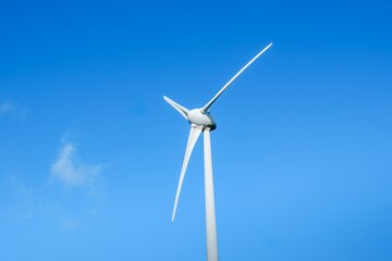 Wind Turbine Against Azure Sky. Clean Energy Power. Close-up view of a wind turbine against a blue sky, symbolizing sustainable energy. The beauty and efficiency of clean, renewable energy sources