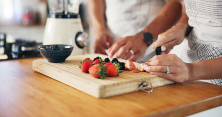 Fruit, smoothie and hands with couple in kitchen for detox drink, health and cutting strawberry. Breakfast, wellness and nutrition with closeup of man and woman at home for protein shake and blender