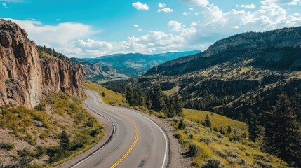 Fototapeta premium Scenic winding road carves through majestic mountain landscape under cloudy sky