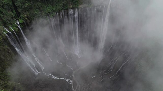 Drone view Tumpak sewu waterfall creating misty clouds in east java