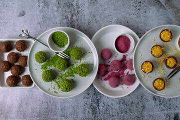 Four types chocolate sweets with different sprinkling on ceramic plates on a gray background. Dessert for a holiday. Handmade. Top view
