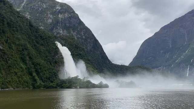 powerful, Lady Bowen Falls falling from high, green, dramatic mountain cliff during a heavy rainfall - Ferry Cruise Through Milford Sound fiord, Fiordland National Park, South Island, New Zealand