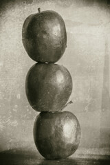 Nostalgic Apple Balance. Three apples stacked in a tower with a retro, aged effect.
