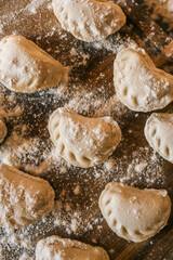 Close-up of raw handmade dumplings on a wooden board dusted with flour, ready to cook