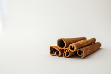 Cinnamon sticks arranged on a white background in soft natural light, showcasing texture and spice...