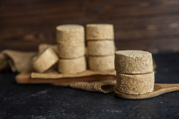 Raw breaded cutlets prepared for frying, stacked on parchment paper and wooden board. Frozen semi-finished meat product on a dark rustic kitchen background