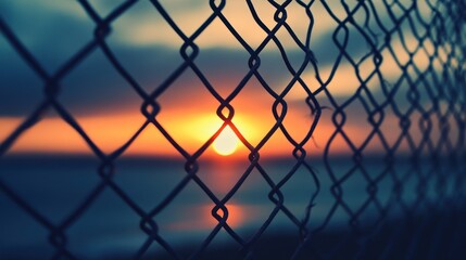 Sunset through chain link fence over water