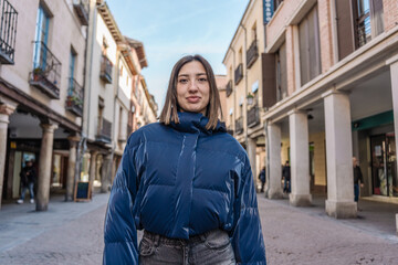 Young woman posing in a city center street wearing a blue puffer jacket © Jorge