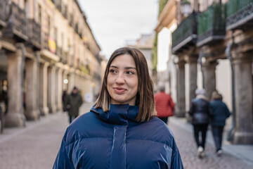 Fototapeta premium Young woman smiling walking down the street in historic city center