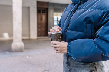 Woman holding disposable coffee cup outdoors in urban setting