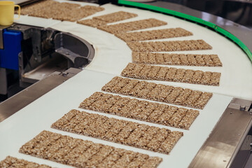 Gozinaki made from sunflower seeds with sugar syrup transferring by conveyor at sweet industry