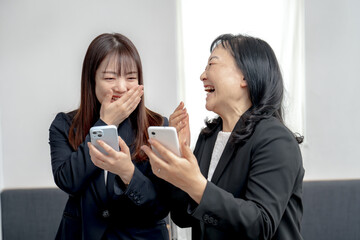 笑い合うスマホを持ったビジネスウーマン