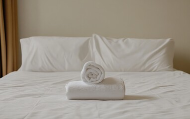 Neatly folded white towels on a white bed, creating a clean and minimalist aesthetic
