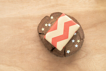 Top view of gift box wrapped in brown paper with red zigzag pattern and gold and silver,...