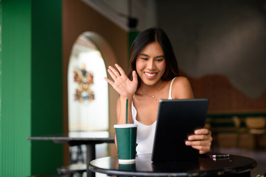 young woman drinking coffee while having video call - Powered by Adobe