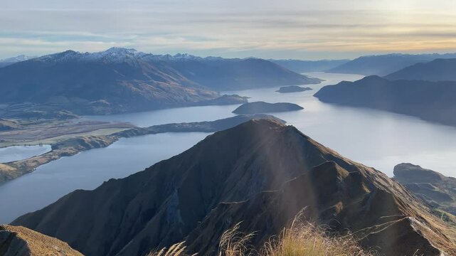 A beautiful sunrise over Wānaka Lake on the famous popular Roys Peak track near Wanaka, Otago, New Zealand, South Island. Massive snow covered mountains in the background