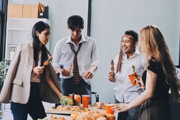Asian office colleagues and friends enjoy a daytime BBQ with pizza and beer, celebrating Halloween and cheering for their favorite soccer team, creating a lively atmosphere filled with joy.