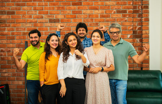 Confident Indian  Asian business team in casuals, smiling, celebrating success in modern workspace