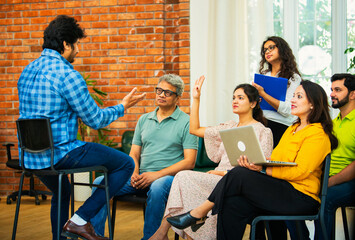 Indian Business manager guiding his team of young professionals in a cozy creative office setting