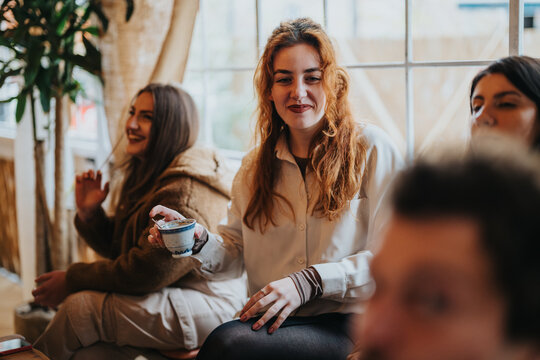 A cheerful group of friends sharing pleasant moments indoors, enjoying coffee and each other's company in a warm, friendly environment.