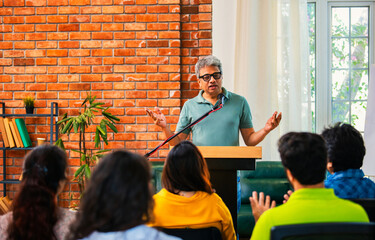 Indian Asian Confident life coach addressing entrepreneurs at a business event with a microphone